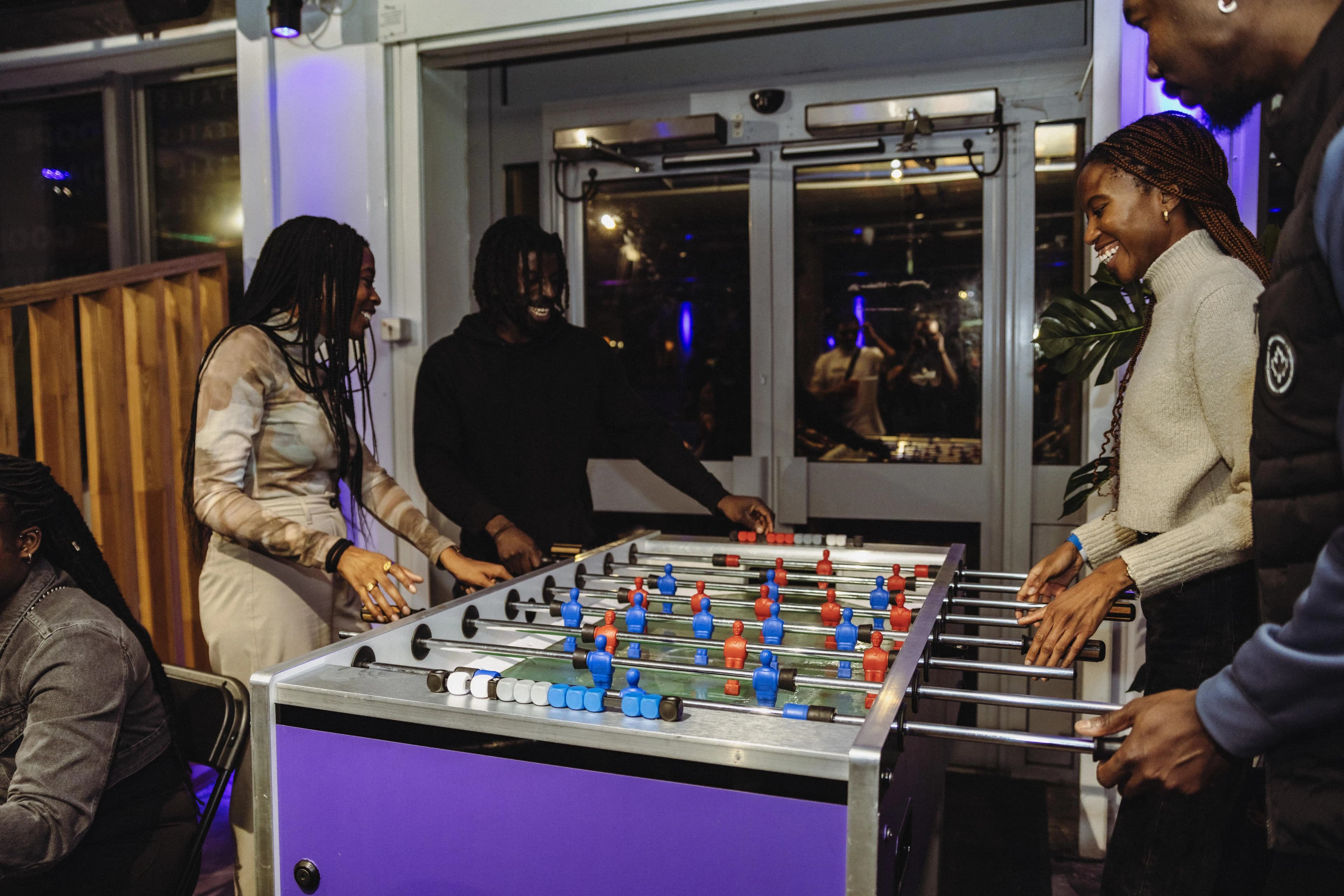 A group enjoying friendly competition around a table football game at KGN
